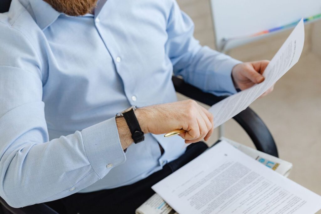 رجل بقميص أزرق يقارن ورقة بمستند آخر أثناء مراجعة ختم نسخة طبق الأصل